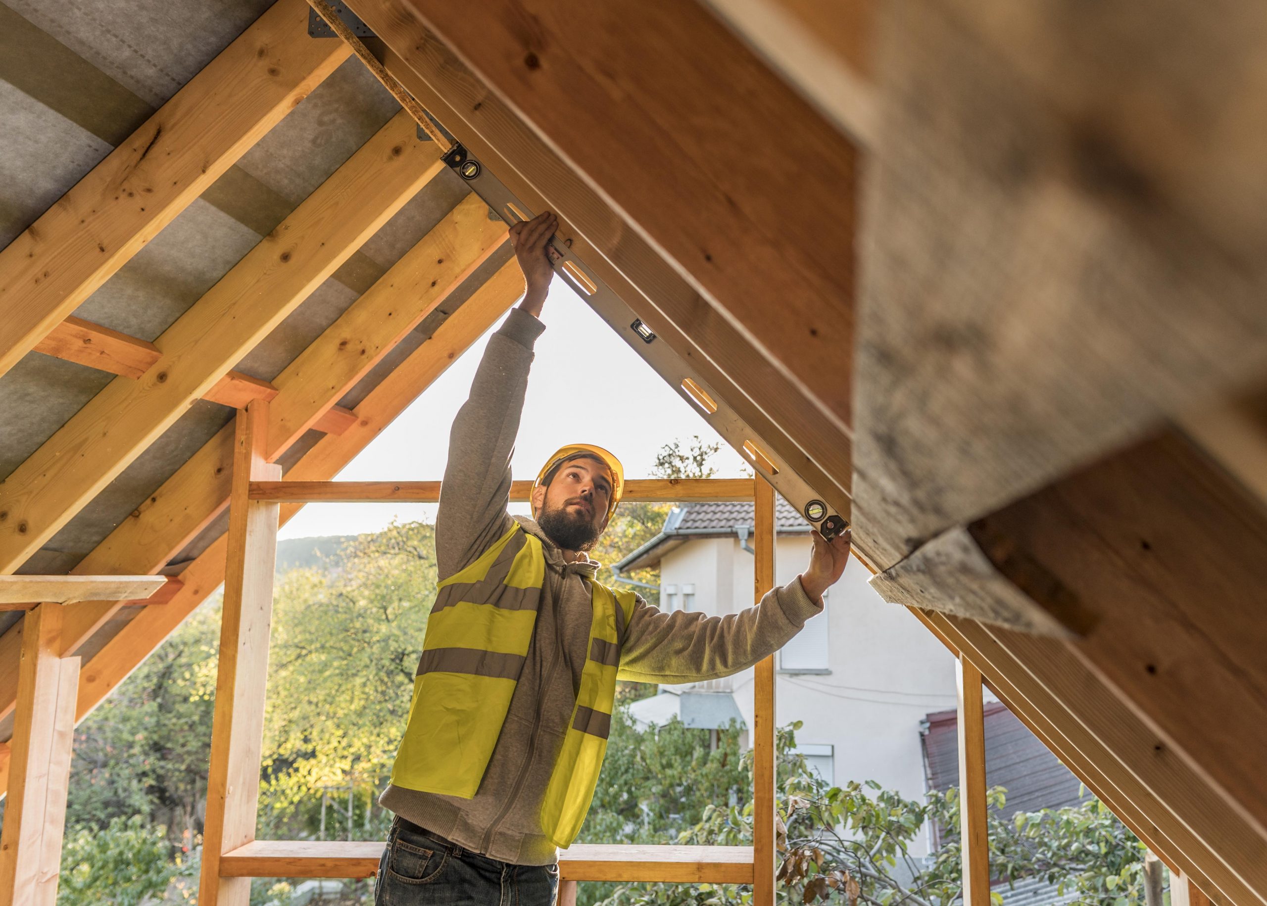 carpenter-man-working-roof Construction worker using a level on a wooden beam