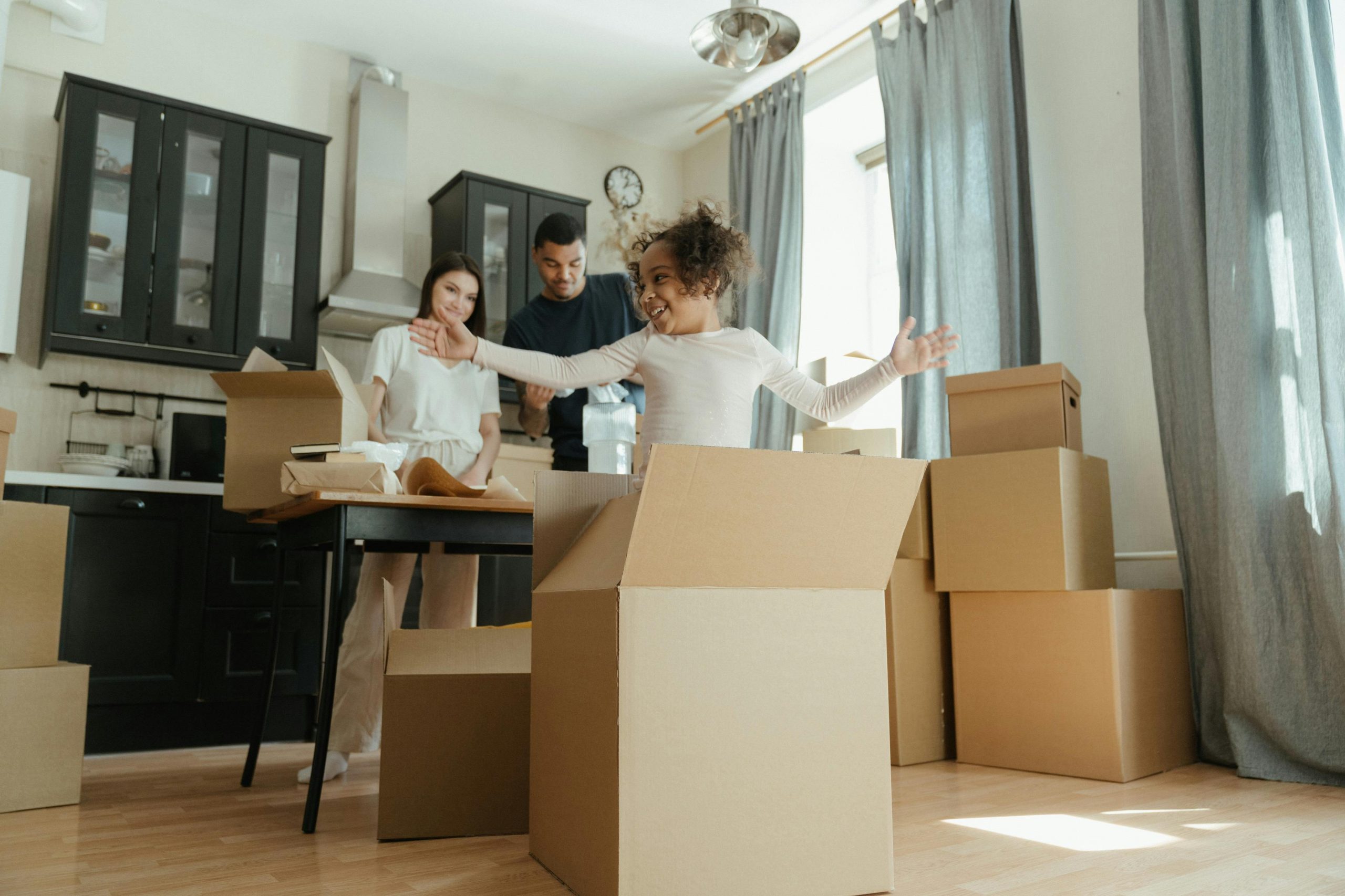 pexels-cottonbro-4569303 A couple unpacking boxes. A child is popping out of the box